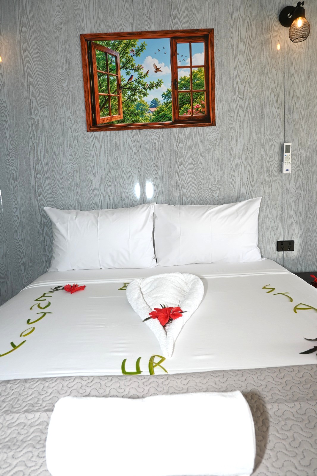 A queen bed with towel art and hibiscus flowers